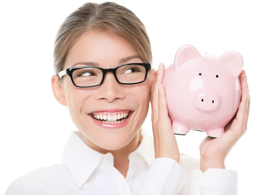 Frau mit Brille schüttelt ihr volles Sparschwein durch Ersparnis