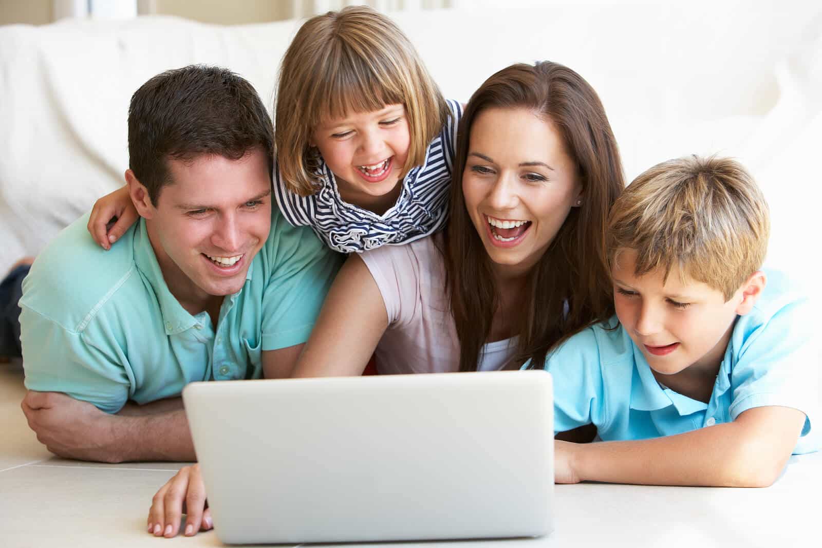Vater, Tochter, Mutter, Sohn schauen zusammen auf einen Laptop