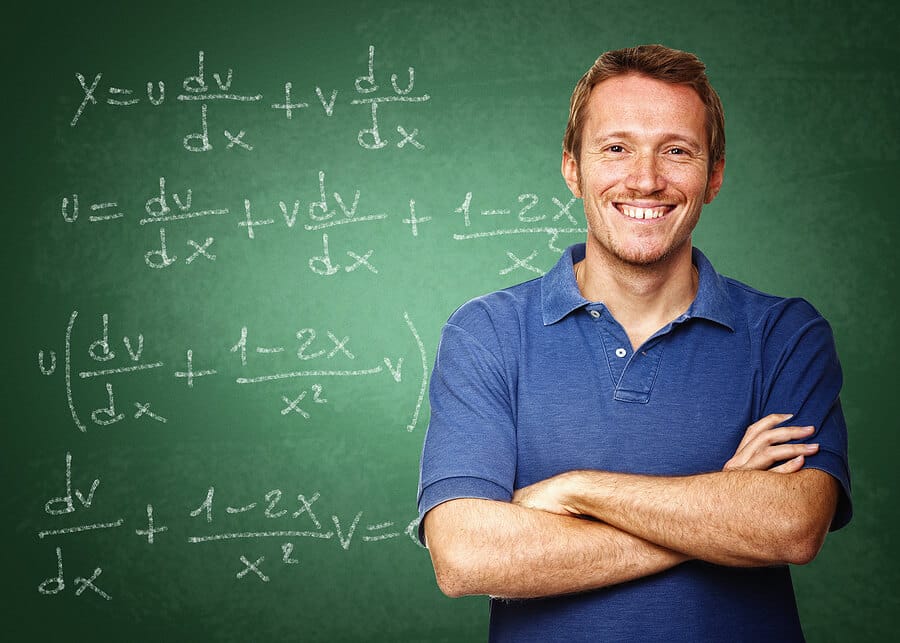 Mathelehrer steht vor Tafel mit Formeln und ist stolz